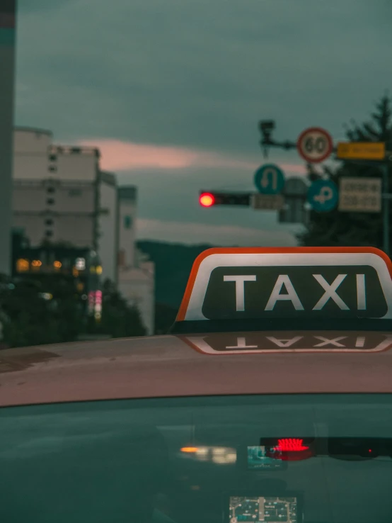 a taxi sign sitting on the roof of a green car