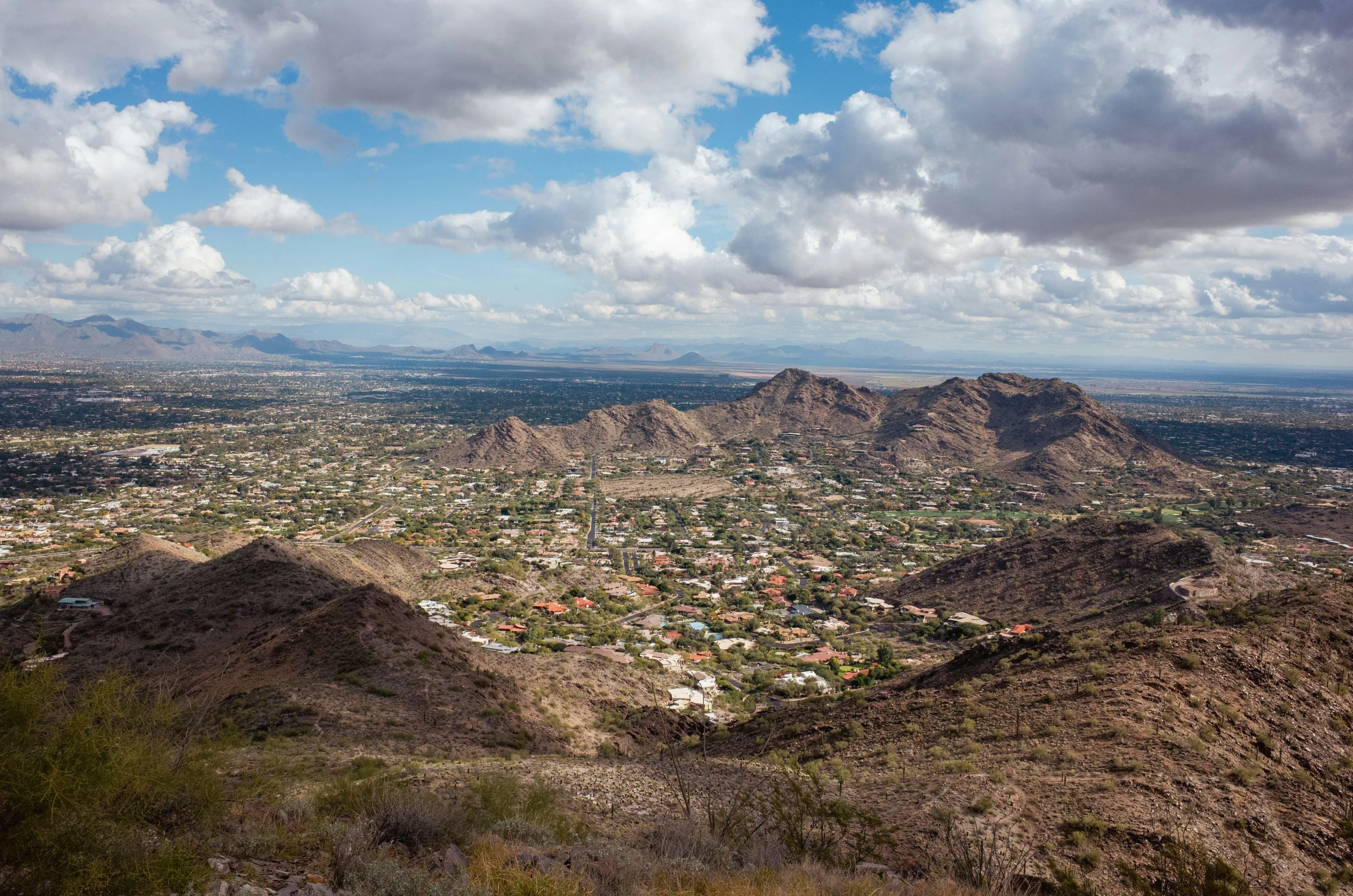 the view from atop a mountain of a town and mountains