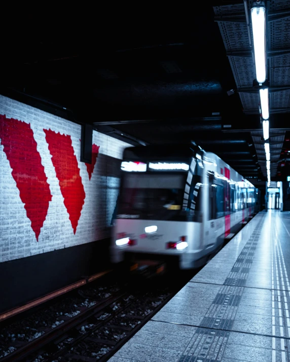 a train in an underground station with red and white graphics