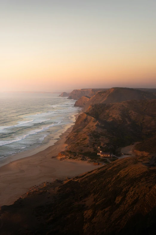 a beach with hills next to it and a long white truck driving down the hill near the water