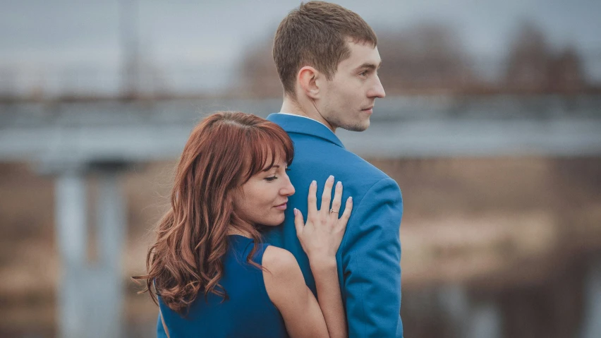 an engaged couple emce in front of a bridge during their engagement session