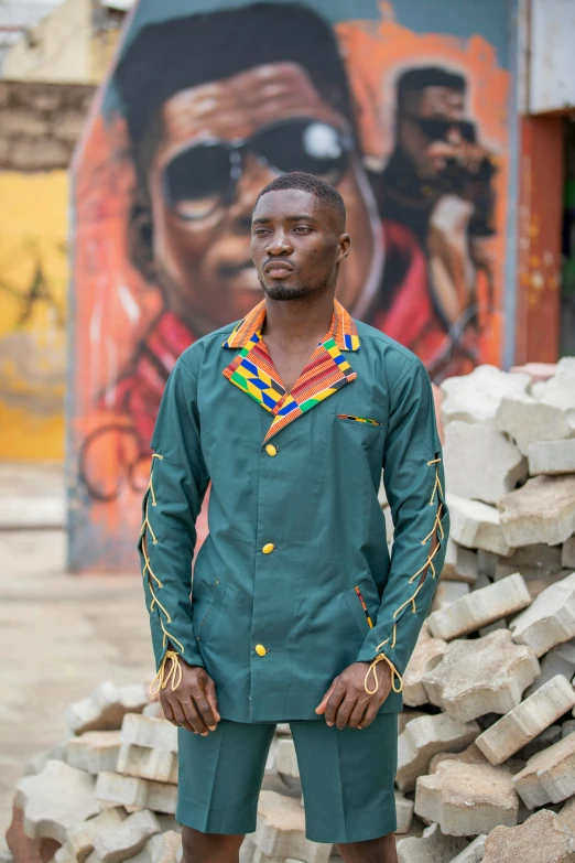 a man wearing a green shirt with red beads stands on a stone slab