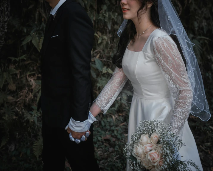 a bride and groom in the woods holding hands