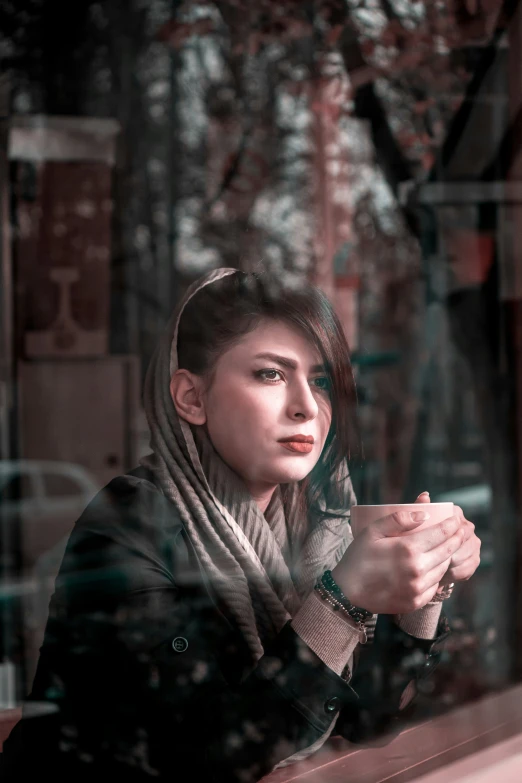 a woman drinking coffee while looking in the window