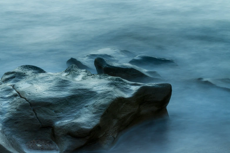 some rocks in the water covered with snow