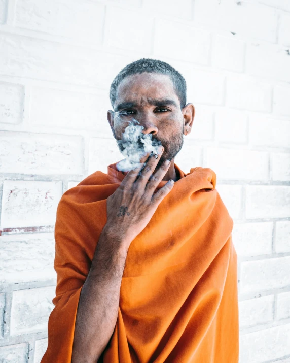 an old man with orange robe and a beard on a white brick wall