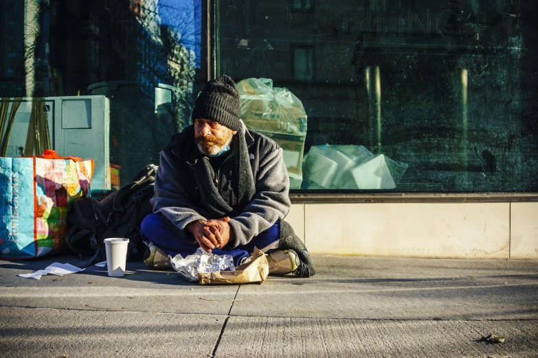 a homeless man sitting outside in front of a building