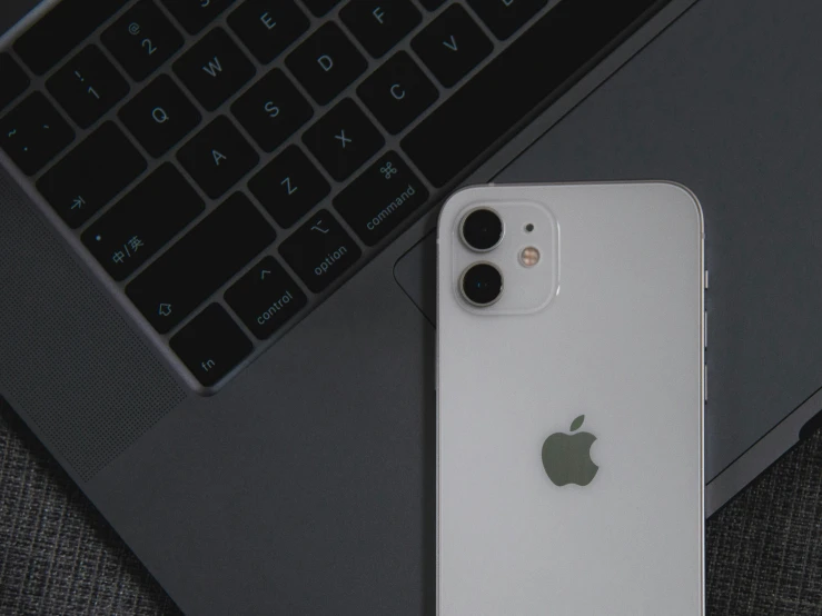 a silver iphone sitting next to a black laptop