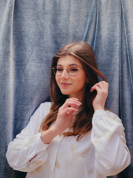 a girl is in front of a curtain and she has glasses