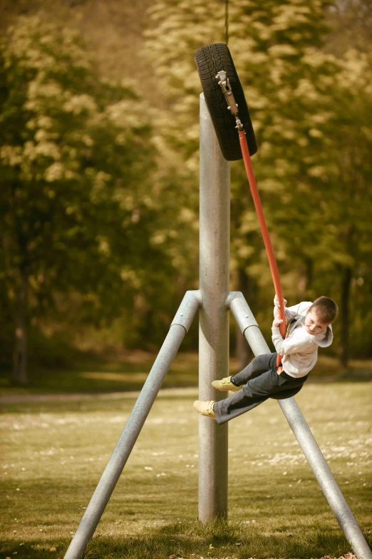 a boy hanging on to a pole while balancing on a rope