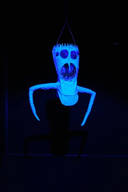 a small blue toy with the shape of a human being projected in the dark