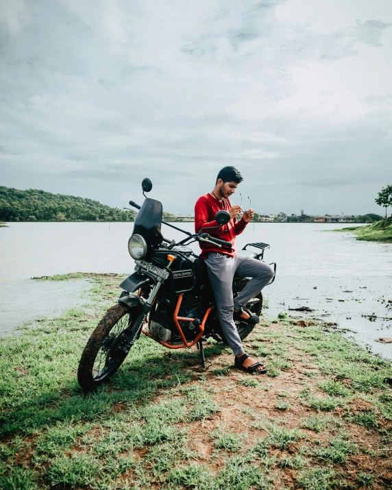 a man sitting on a motorcycle next to the water