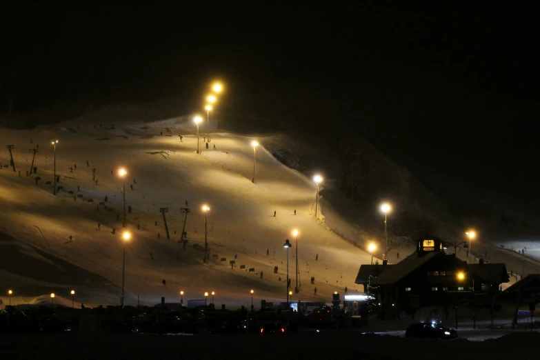 a nighttime ski resort with snow falling on the slopes