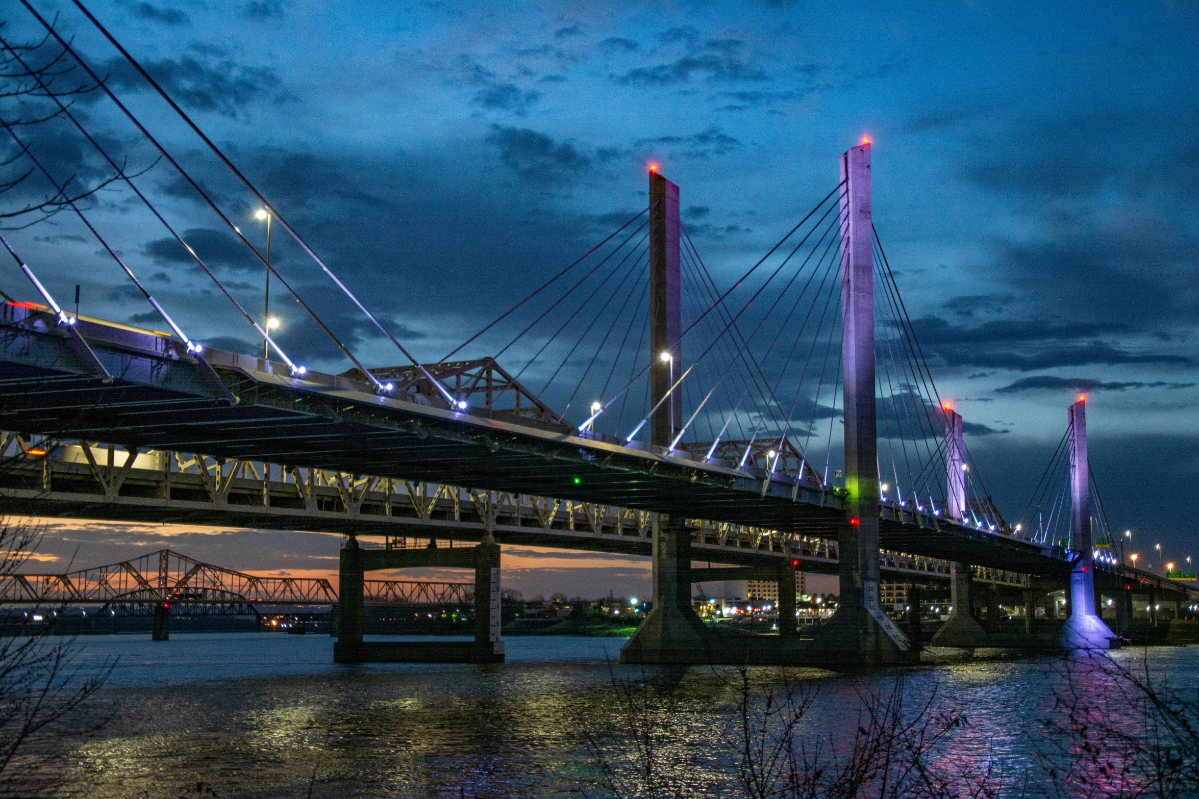 a night scene showing a lit bridge with purple and blue lighting