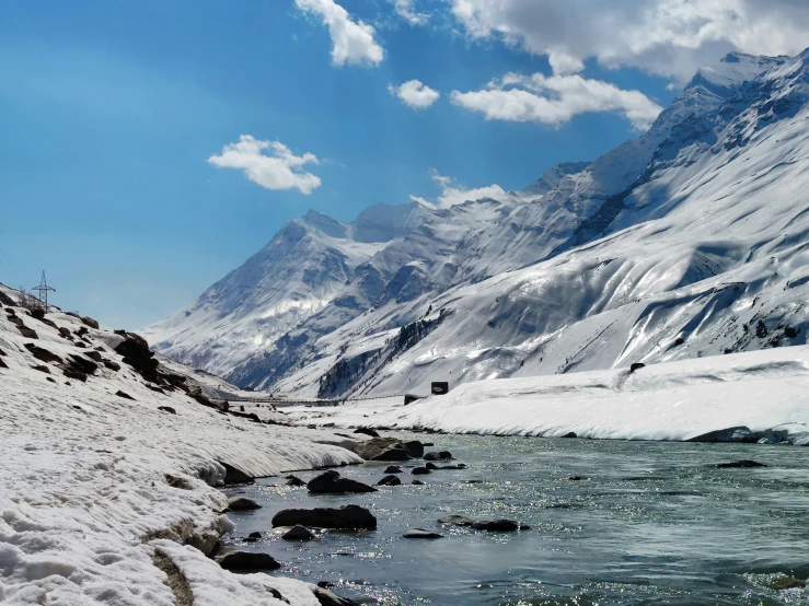 a body of water next to a snowy mountain