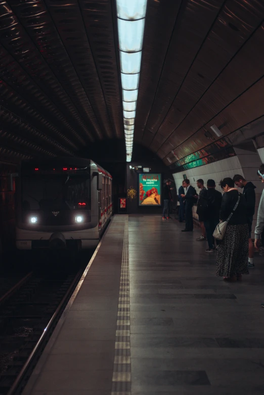many people stand at a platform waiting for the subway