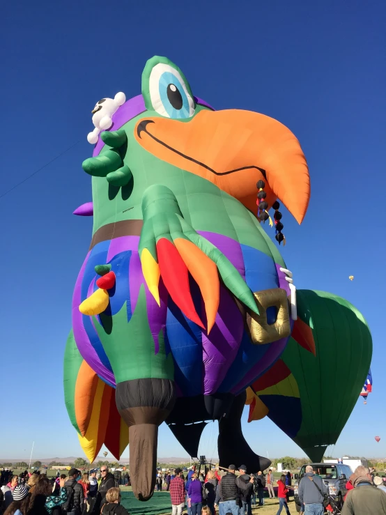 the large colorful kite is in the shape of a bird