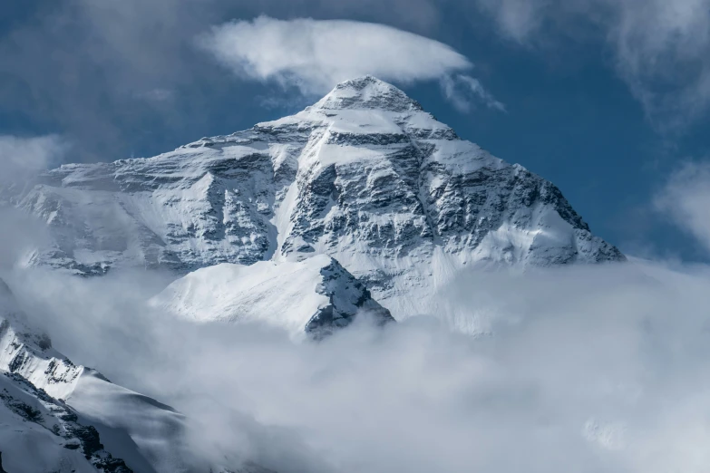 a snow covered mountain in the distance surrounded by clouds