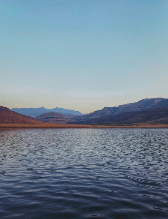 mountains are seen from the edge of the lake