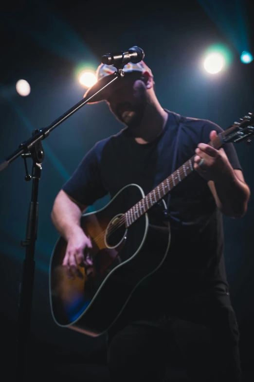 a man standing on a stage with an acoustic guitar