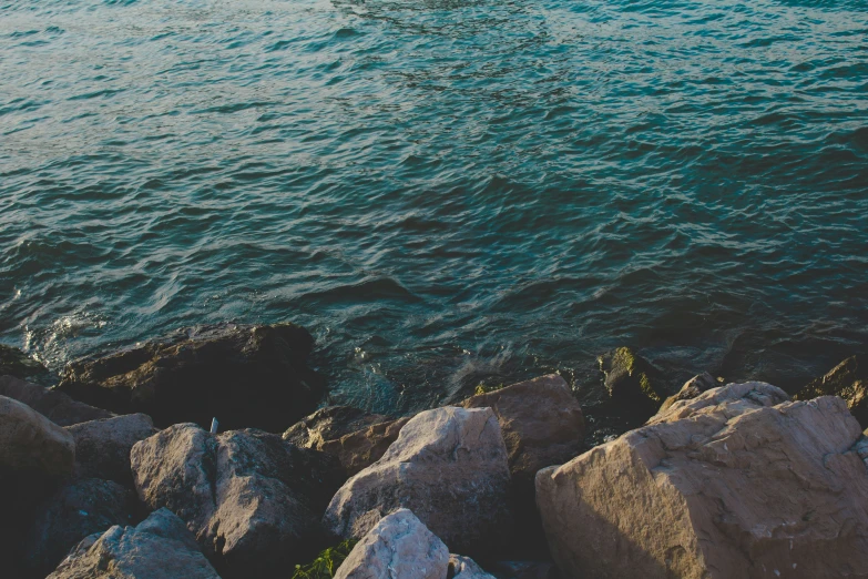 some rocks by the water with two boats