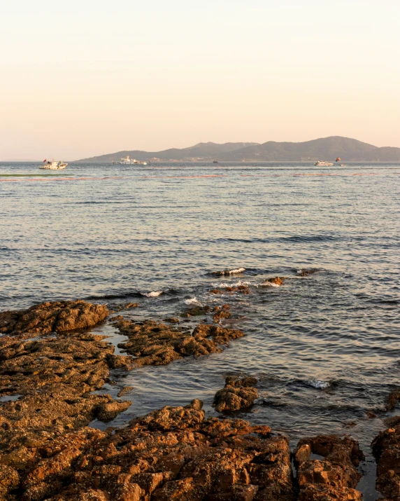 boats in the water and rocks on the shoreline