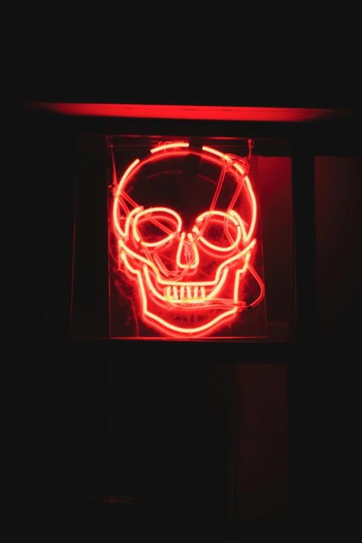 a neon sign with a skull wearing sunglasses on it