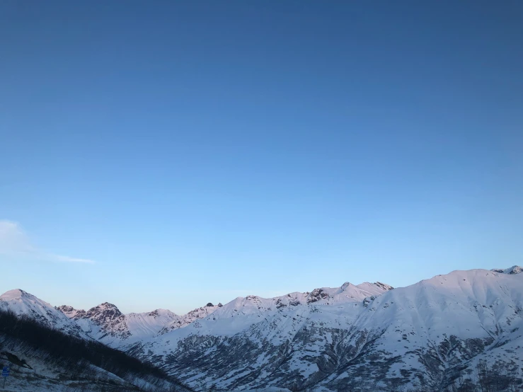 the snow - capped mountains have some clear blue skies