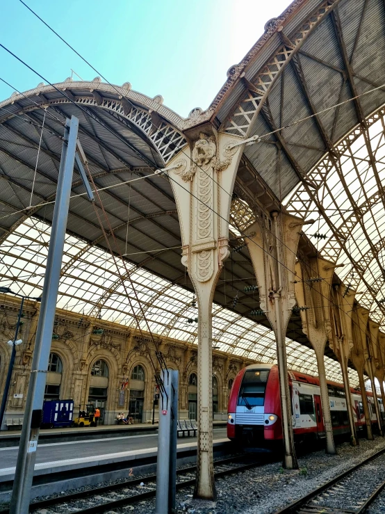 a train sits on the tracks underneath a very large roof