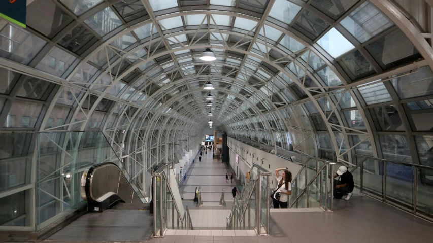 a glass covered hallway that features escalators and escalators