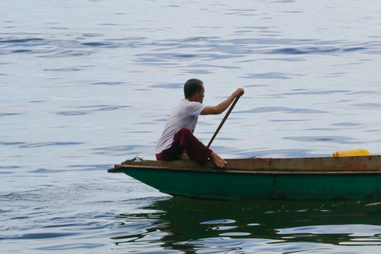 a man paddling in a green boat on top of the water