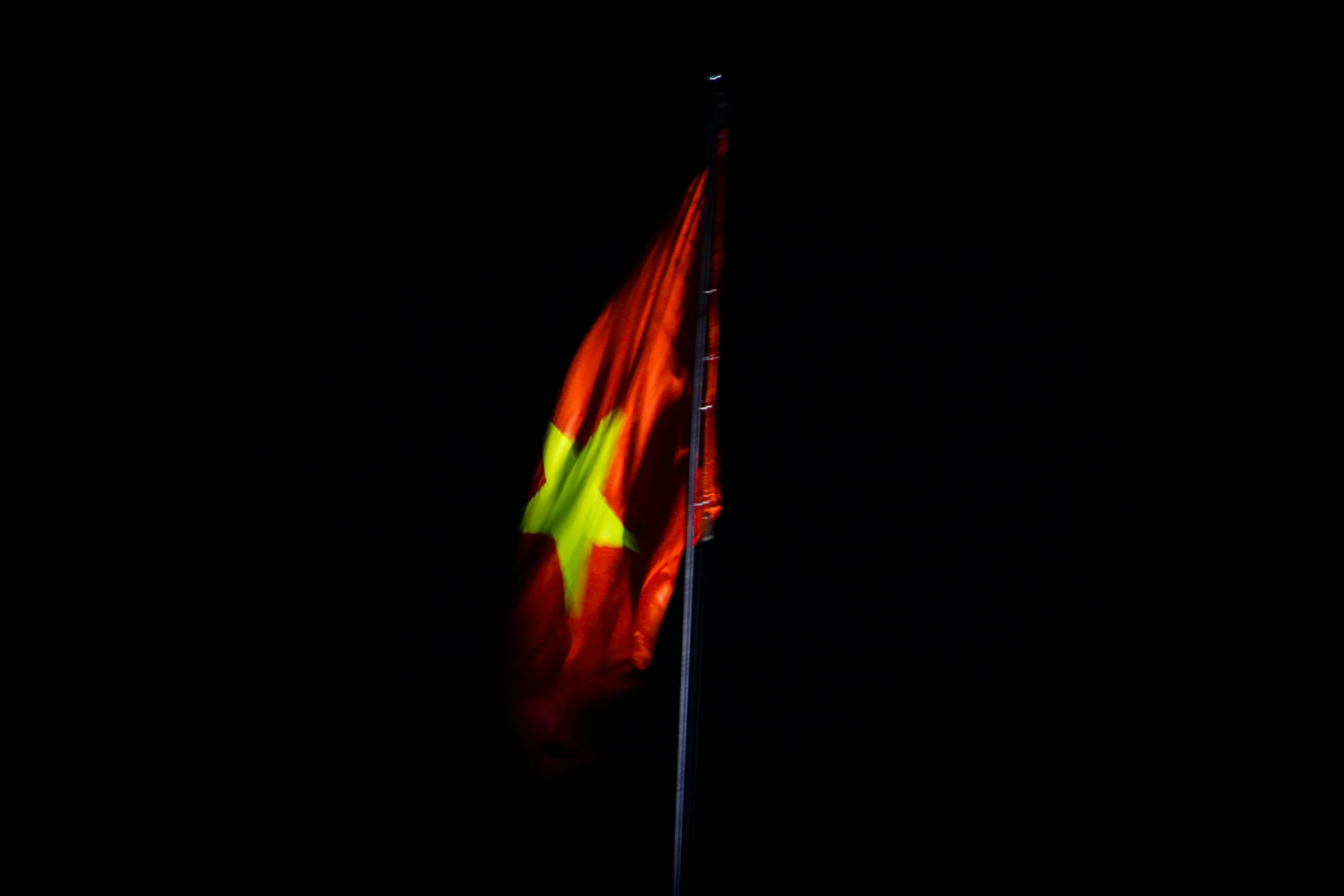 an illuminated flag is seen against a black background