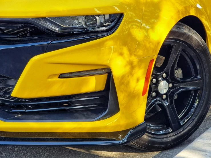 the side of a yellow camaro with black trim