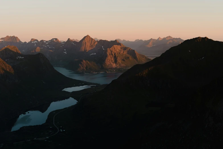 a valley that has several mountains with a body of water surrounded by a bunch of grass