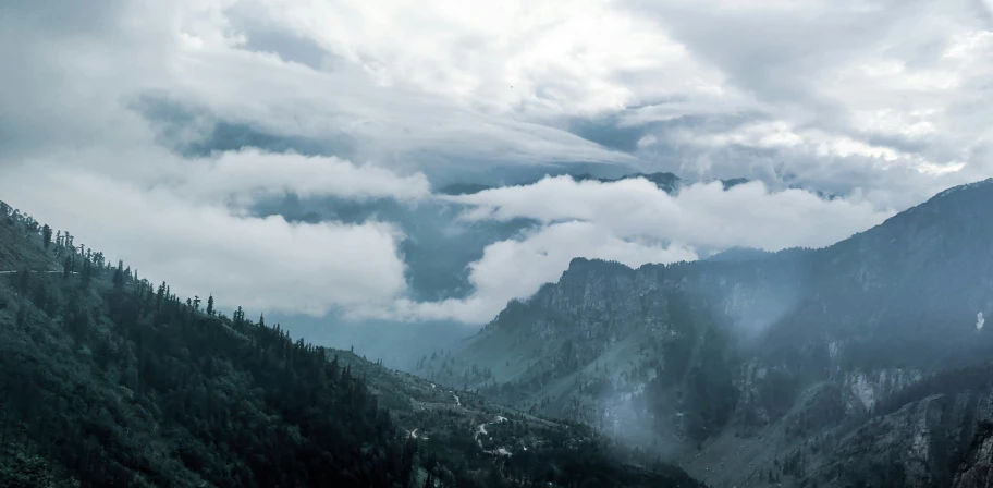 several people stand on a mountain top with mountains and clouds in the background