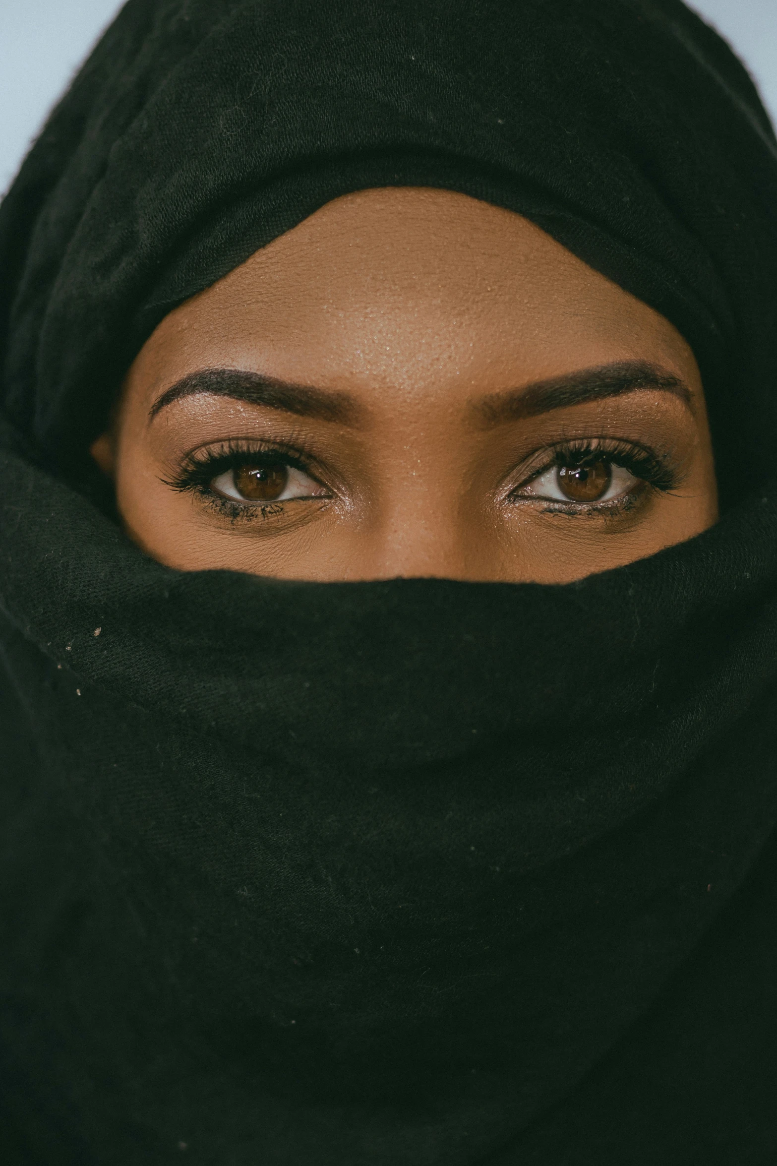 a woman in a black outfit with a large pair of brown eyes