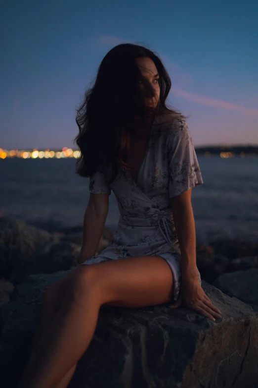 the girl sitting on a rock looks down