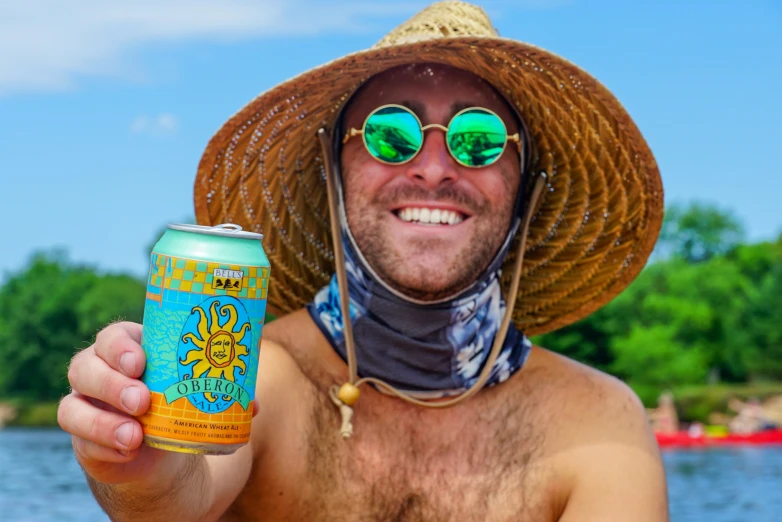 a man wearing sun glasses and hat, holding a can