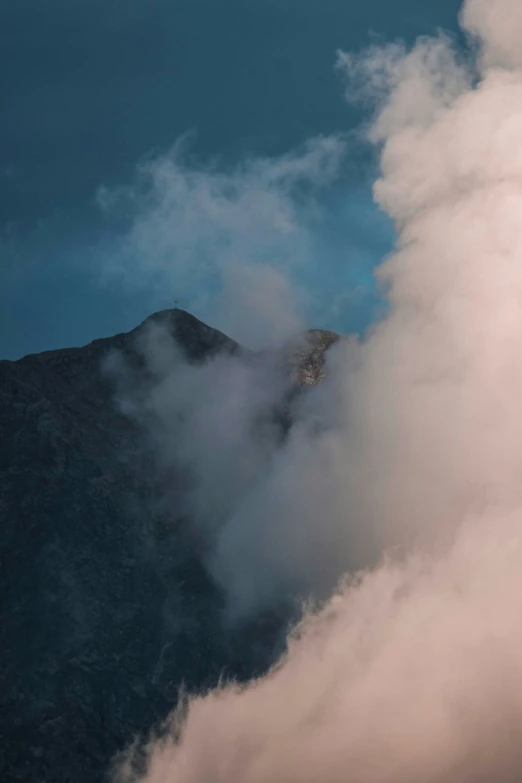 the clouds hover over a mountain as an airplane is flying overhead