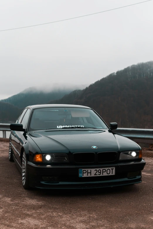 a black bmw is parked next to a body of water