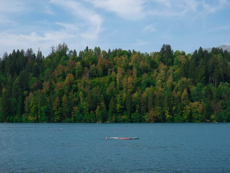 a red boat sitting in a lake by some trees