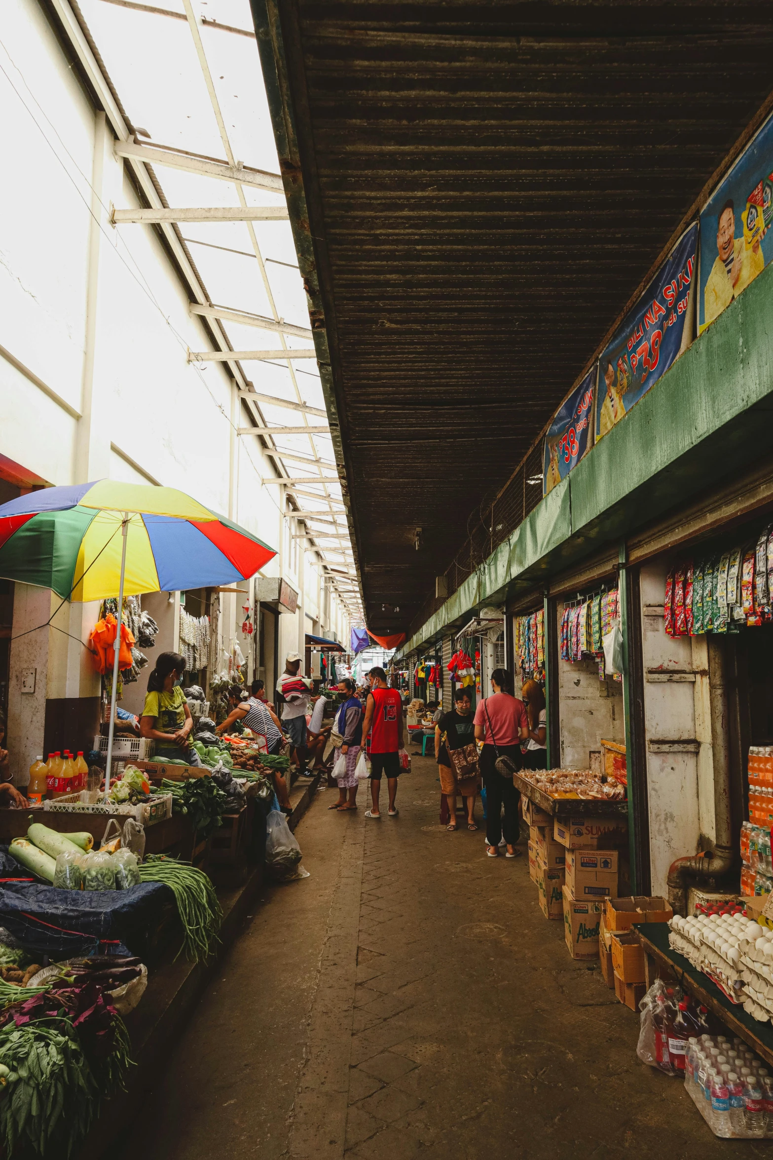 an outdoor market with an umbrella and some people shopping