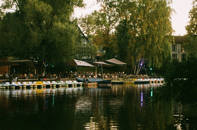 several boats are lined up along a river with umbrellas on it