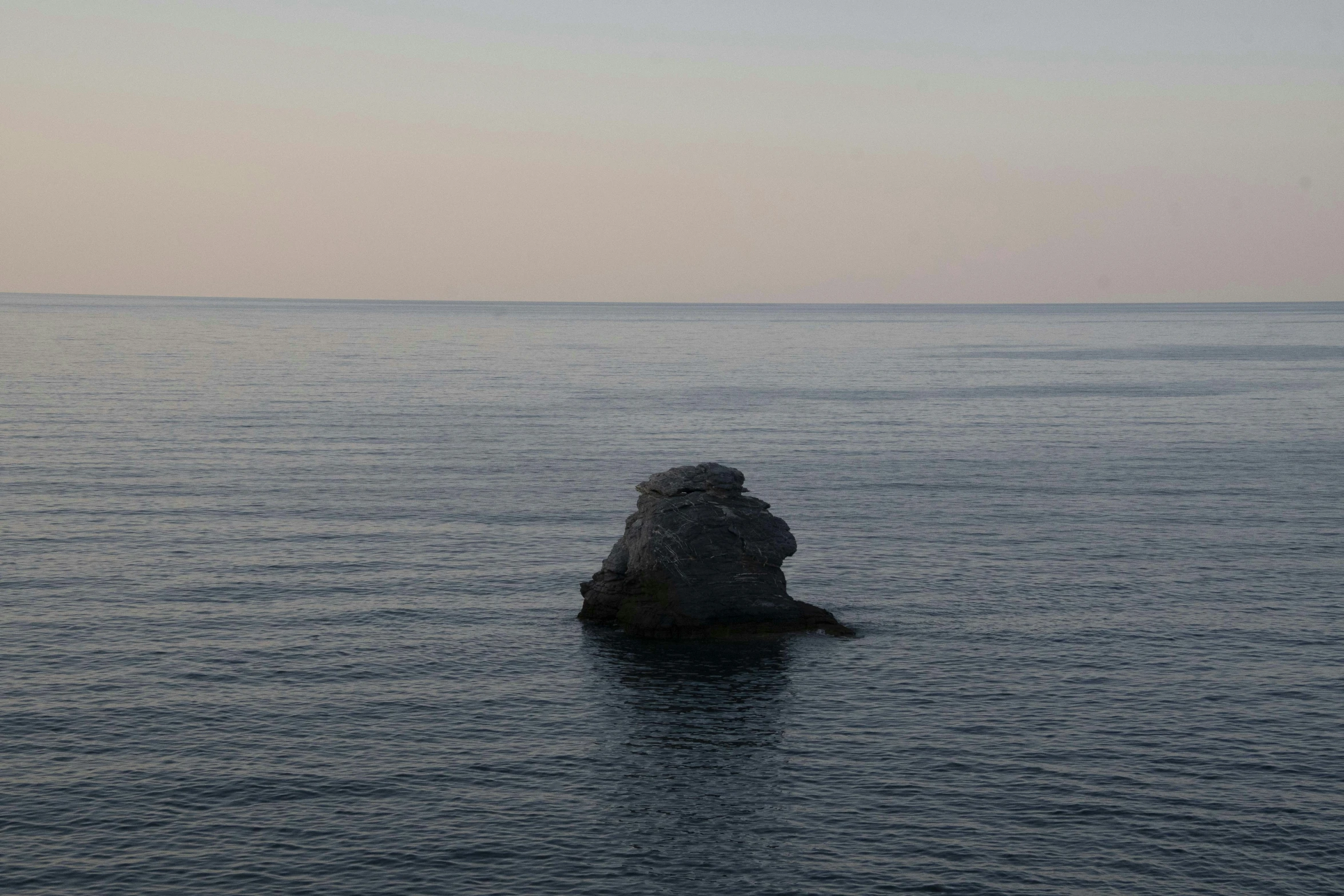 a very tall rock sticking out in the middle of the water