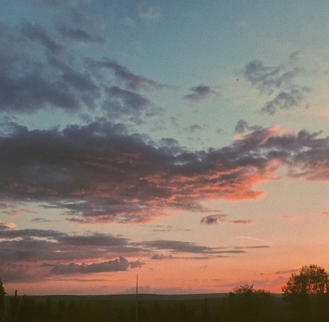 the setting sun in the sky looking across the treetops