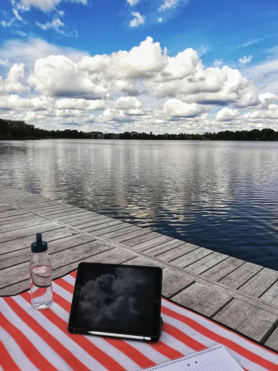 an ipad and pen on a dock near the water