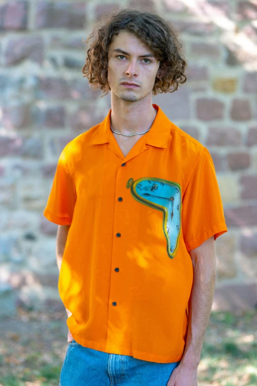 a boy wearing an orange shirt with a green painted piece on it