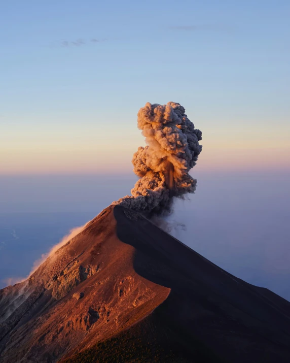 a plume of smoke rises over a barren mountain side