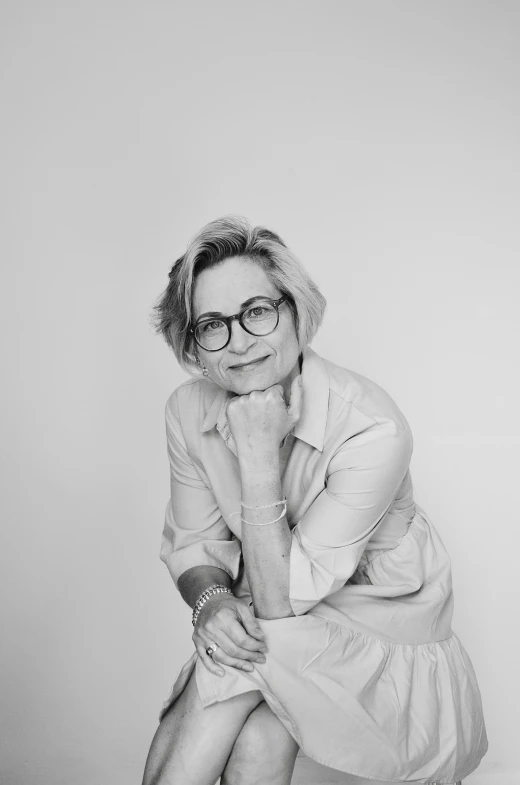 a woman in glasses sits on the ground and poses