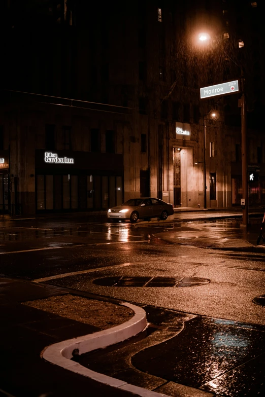 a wet street is shown with a building lit up at night